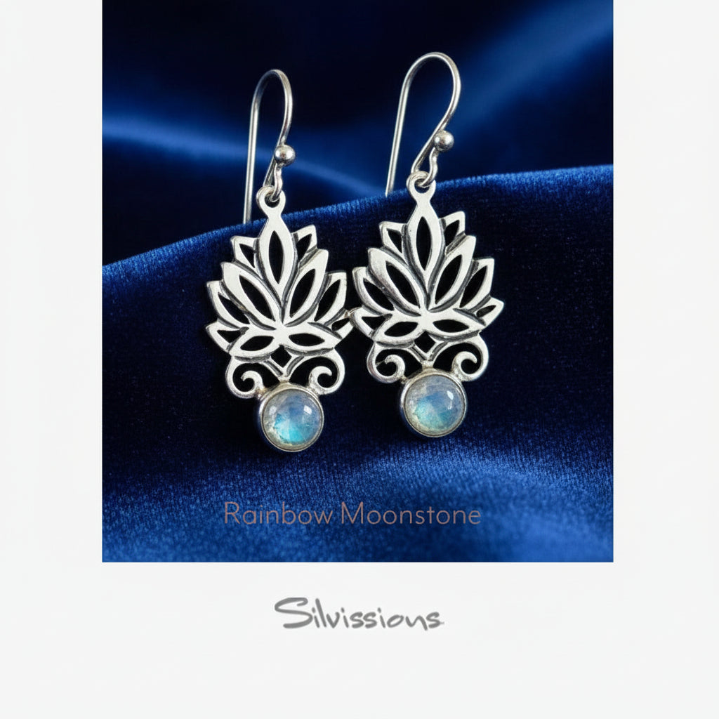 Silver earrings with rainbow moonstone stones on a blue satin background, featuring the brand 'Silvissions'.