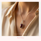 Necklace with a red pendant worn by a person, brand 'Silvissions' visible