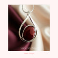 Silver pendant with red onyx stone on a satin background, featuring the Silvissions brand.