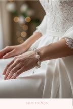 Close-up of a person wearing a white lace dress with a bracelet, blurred lights in the background