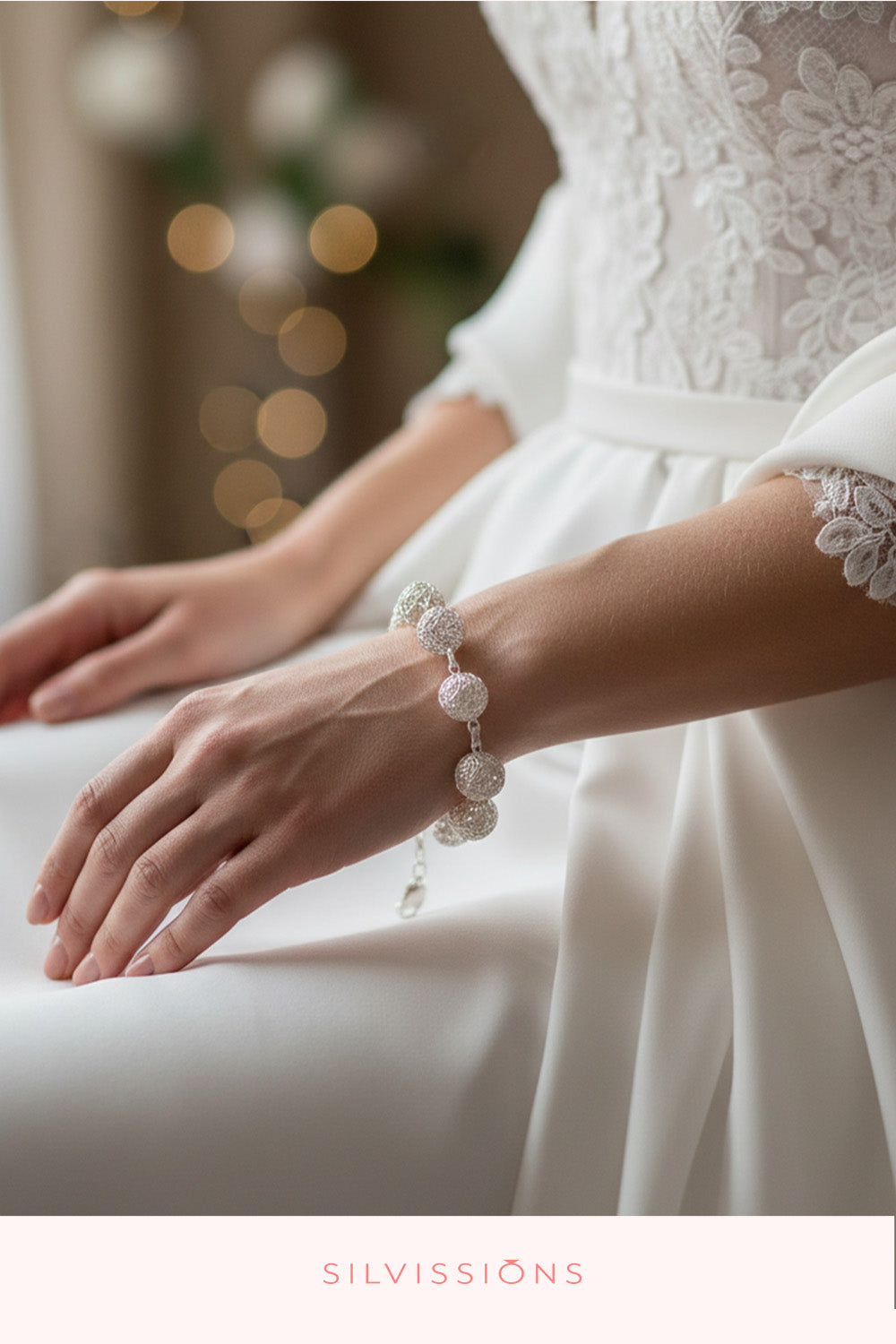 Close-up of a person wearing a white lace dress with a bracelet, blurred lights in the background
