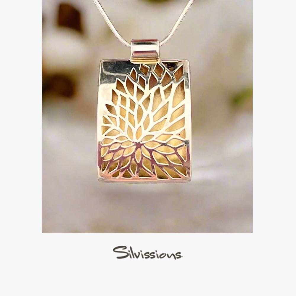 Silver and gold pendant with 'Silvissions' branding on a blurred background