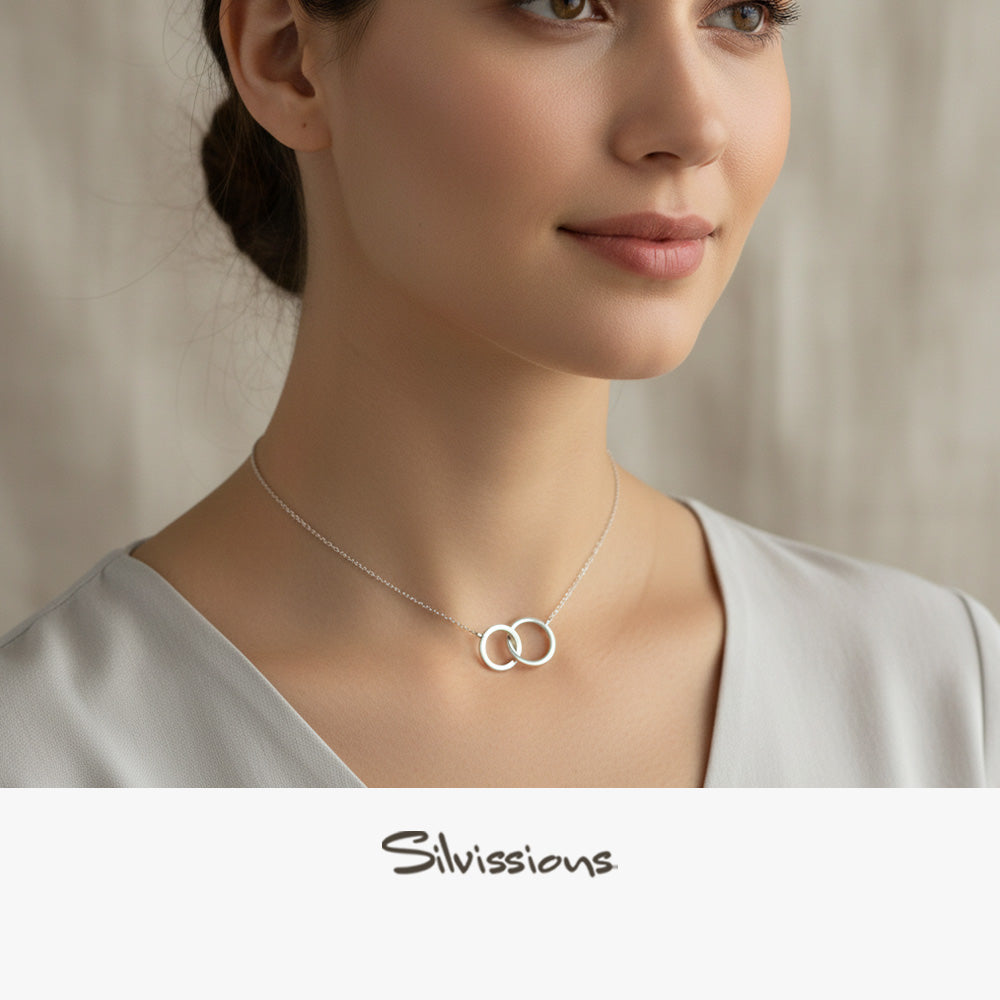 Silver necklace with interlocking rings worn by a person, brand 'Silvissions' visible