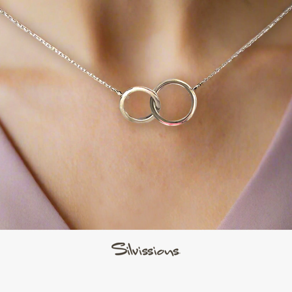Silver necklace with interlocking rings worn by a person, brand 'Silvissions' visible