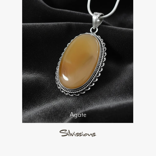 Agate pendant on a silver chain against black fabric, branded 'Silvissions'.