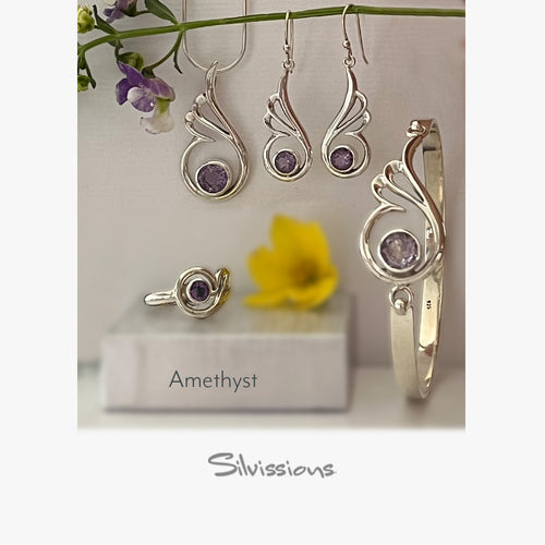 Silver jewelry set with amethyst stones on a white background with flowers.