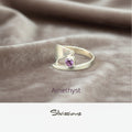 Silver ring with a purple gemstone on a beige fabric background, featuring the brand 'Silvissions'.