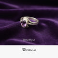 Silver ring with amethyst gemstone on purple fabric, branded 'Silvissions'.