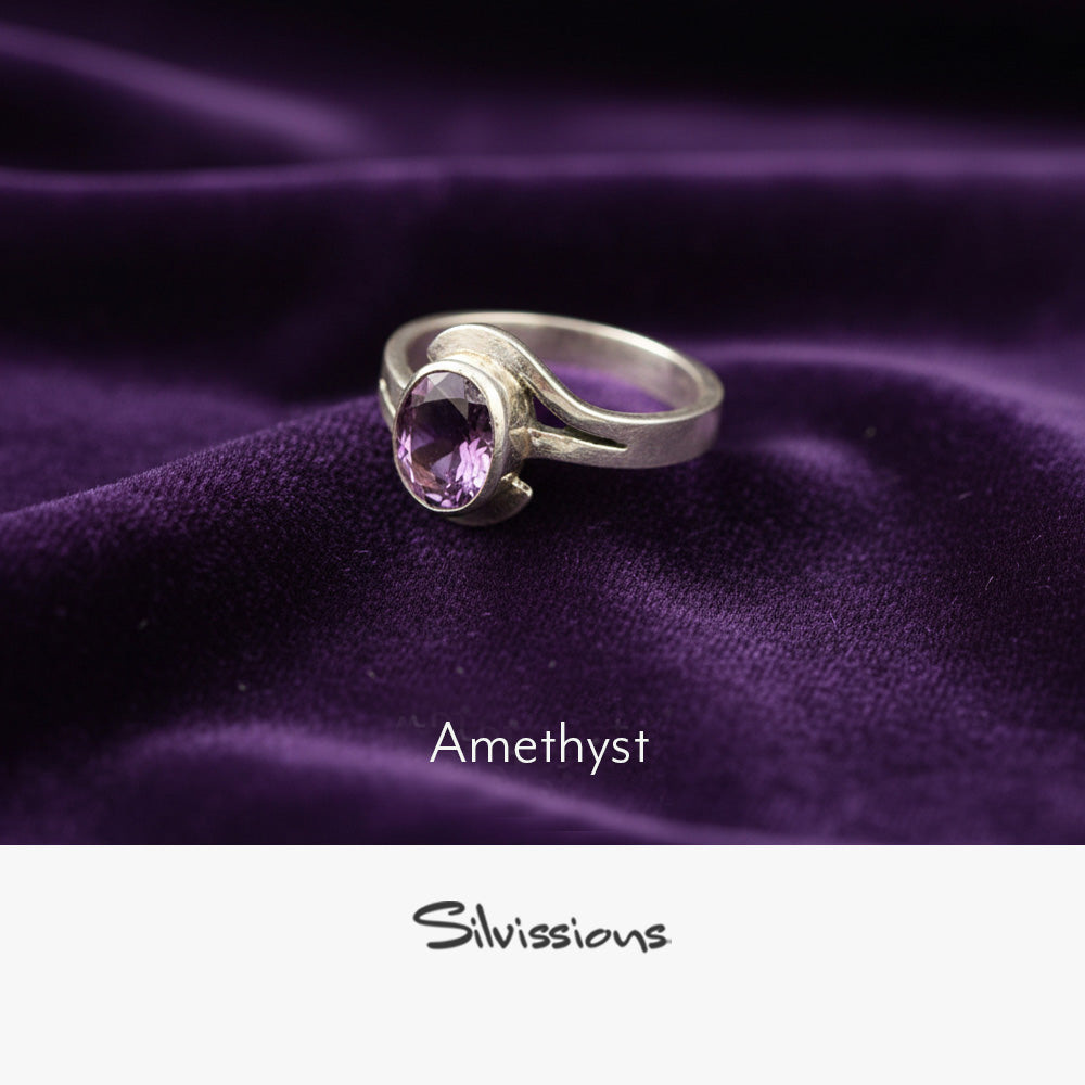 Silver ring with amethyst gemstone on purple fabric, branded 'Silvissions'.