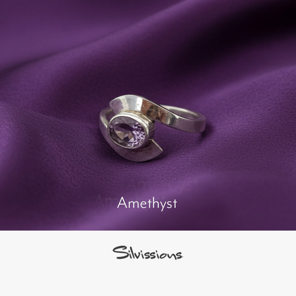 Silver ring with amethyst gemstone on purple fabric, featuring the brand 'Silvissions'.