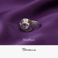 Silver ring with amethyst gemstone on purple fabric, featuring the brand 'Silvissions'.