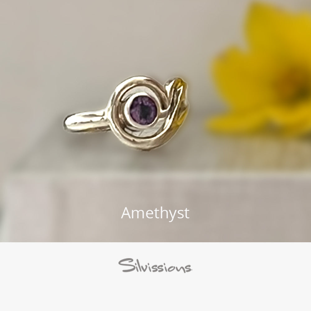Silver ring with a purple gemstone on a neutral background, featuring the brand 'Silvissions'.