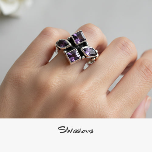 Silver earring with purple gemstones on a blurred background, brand 'Silvissions' visible.