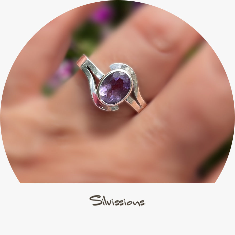 Silver ring with a purple gemstone on a blurred background, featuring the brand 'Silvissions'.