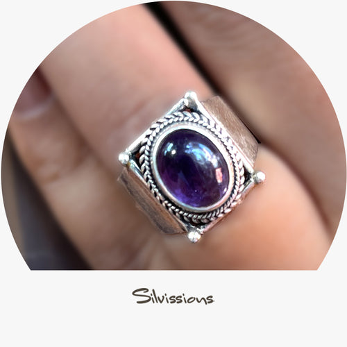 Silver ring with a purple gemstone on a finger, branded 'Silvissions'.