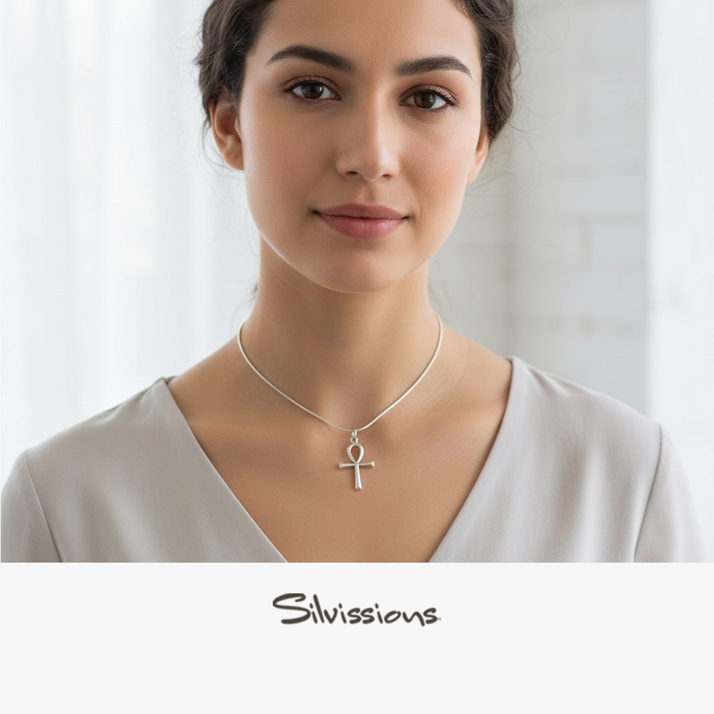 Woman wearing a silver necklace with an ankh pendant against a plain background, featuring the Silvions brand.