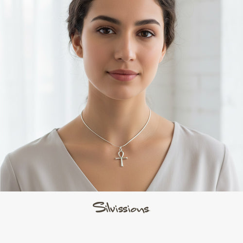 Woman wearing a silver necklace with an ankh pendant against a plain background, featuring the Silvions brand.