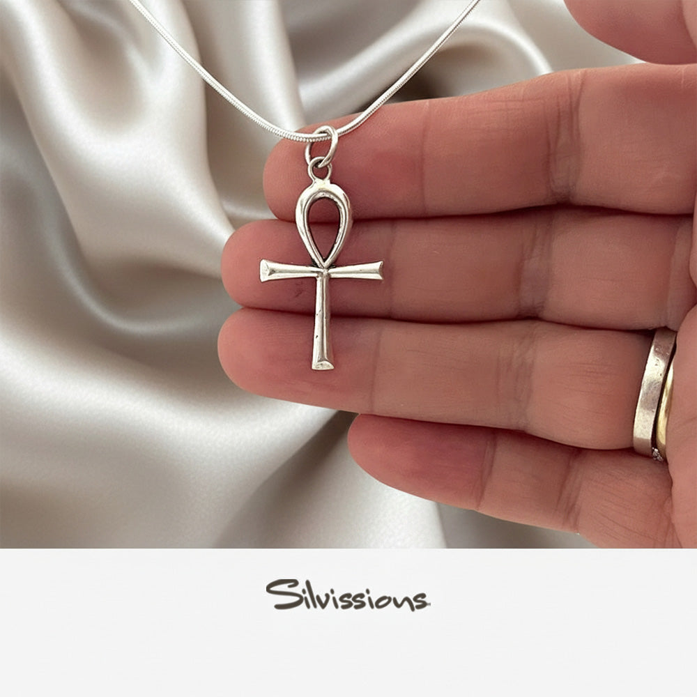 Silver Ankh pendant held in a hand against a satin background, with 'Silvissions' branding.
