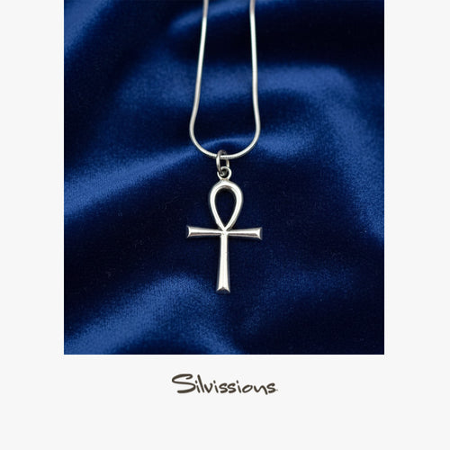 Silver ankh pendant necklace on a blue satin background with 'Silvissions' branding.