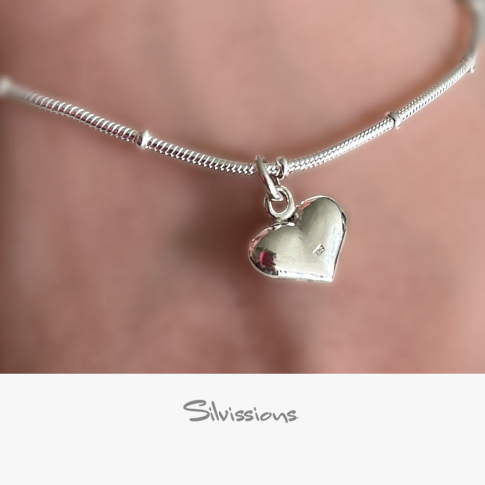 Silver ankle bracelet with a heart-shaped charm on a blurred background, featuring the brand 'Silvissions'.