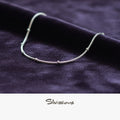 Silver ankle bracelet on a dark fabric background with 'Silvissions' branding.