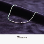 Silver ankle bracelet on a dark fabric background with 'Silvissions' branding.