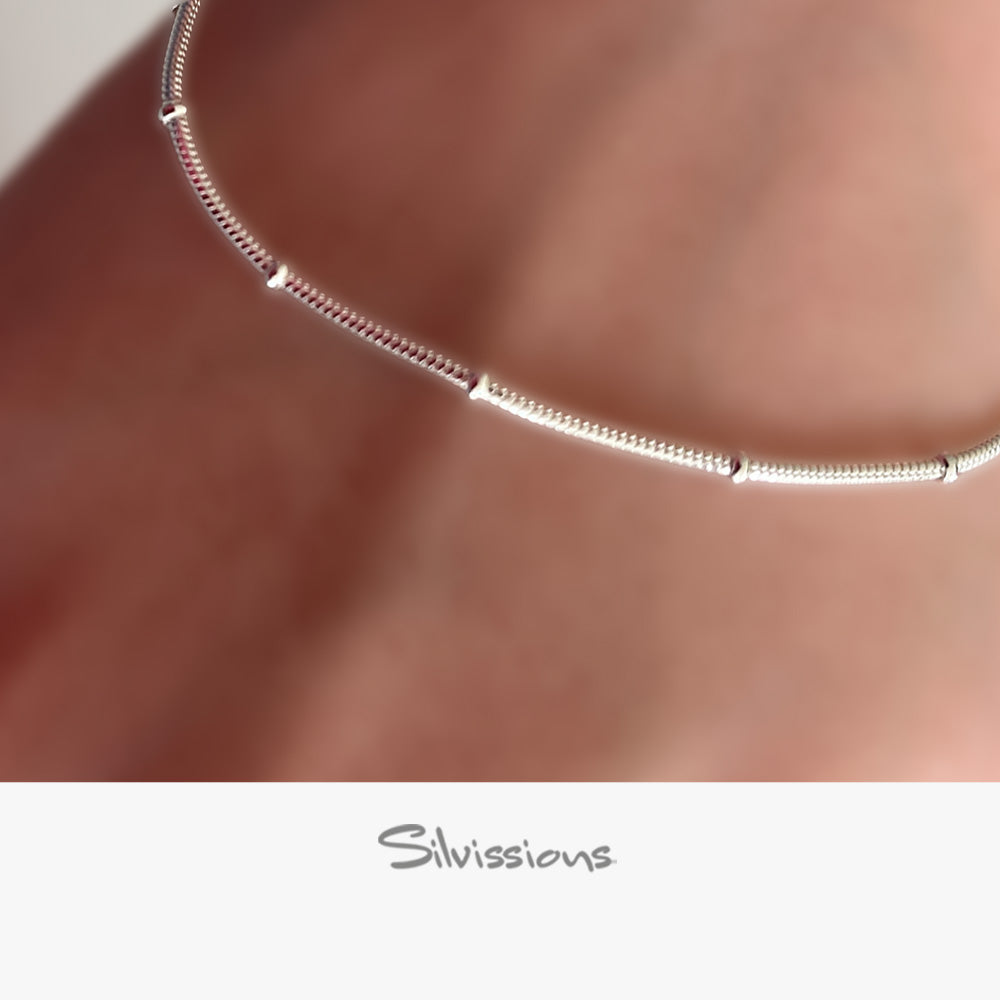 Silver ankle bracelet on a person's wrist with 'Silvissions' branding.