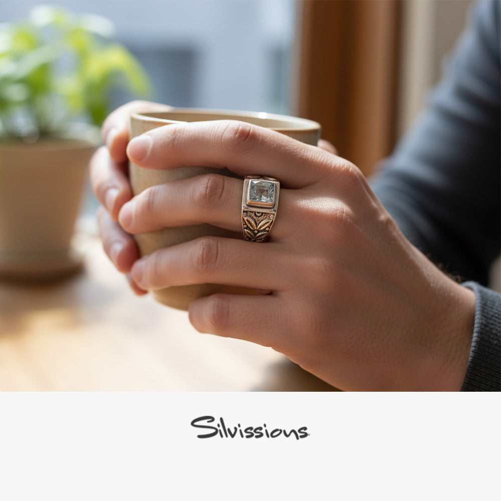 Hand holding a cup with a decorative ring, blurred background with 'Silvissions' branding.