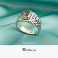 Silver ring with gemstone on a teal fabric background, featuring the brand 'Silvissions'.