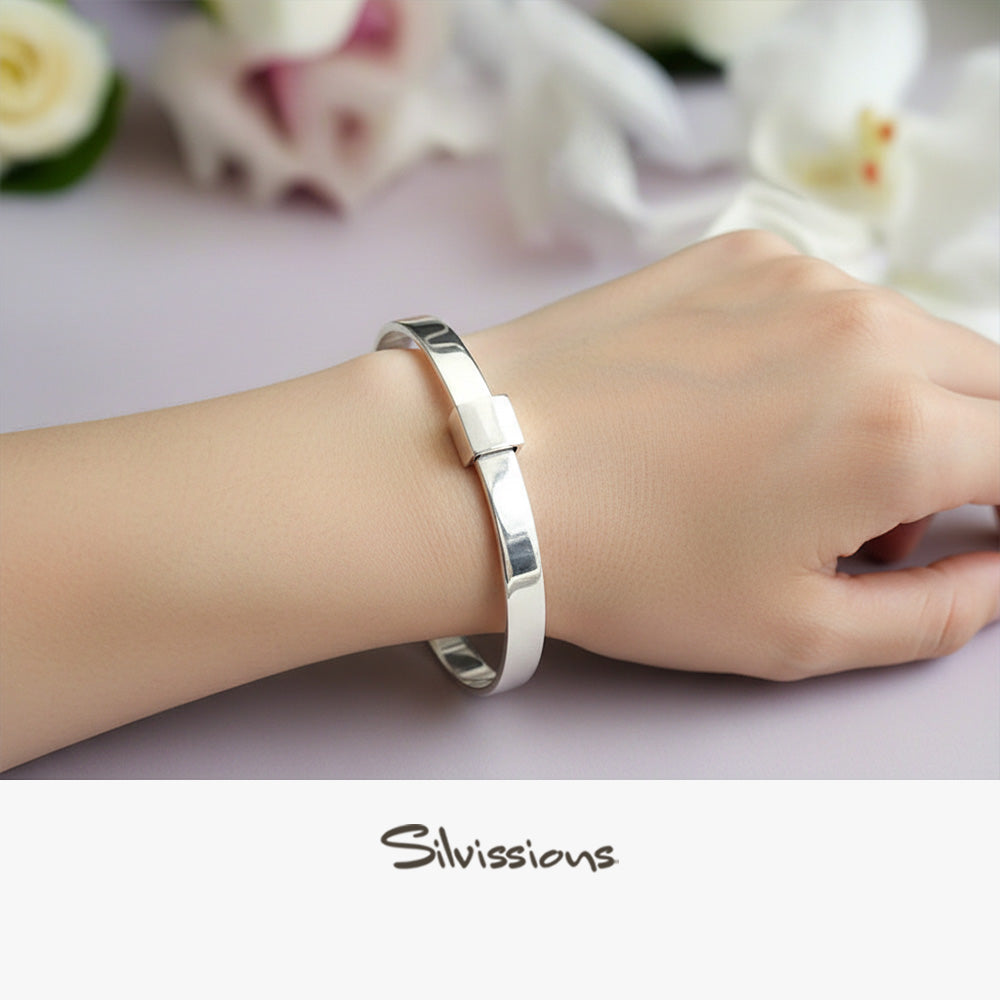 Silver bracelet on a wrist with a blurred floral background, featuring the brand 'Silvissions'.