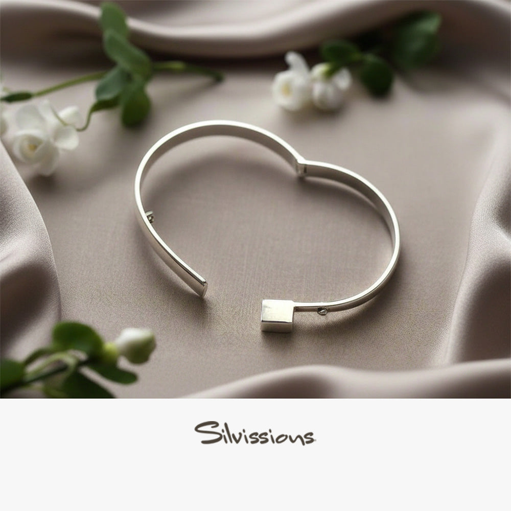 Silver bracelet on a soft beige surface with flowers, featuring the brand 'Silvissions'.