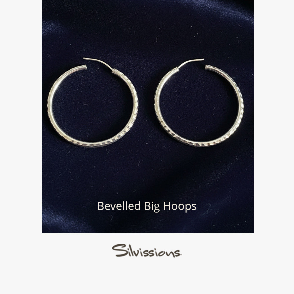 Pair of silver bevelled hoop earrings on a dark blue background with 'Silvissions' branding.