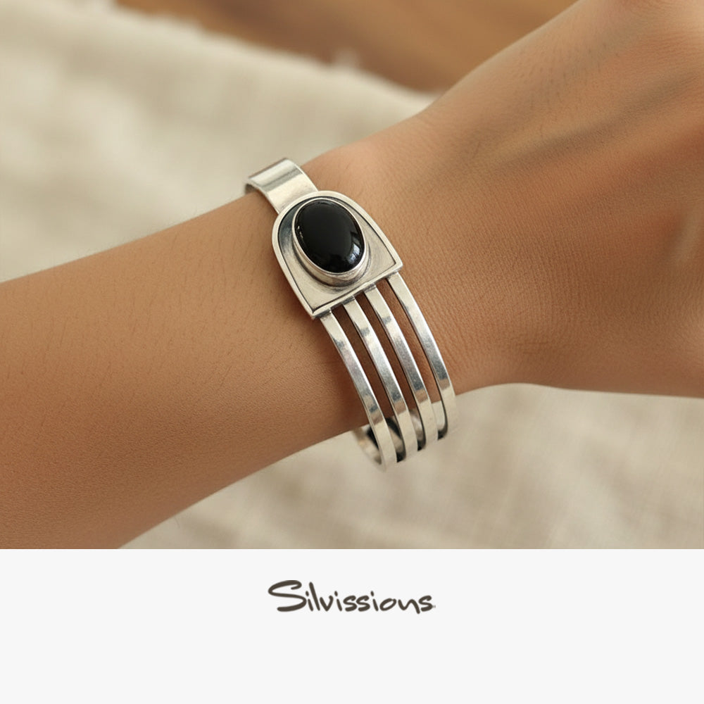Silver bracelet with a black stone on a wrist, branded 'Silvissions'.