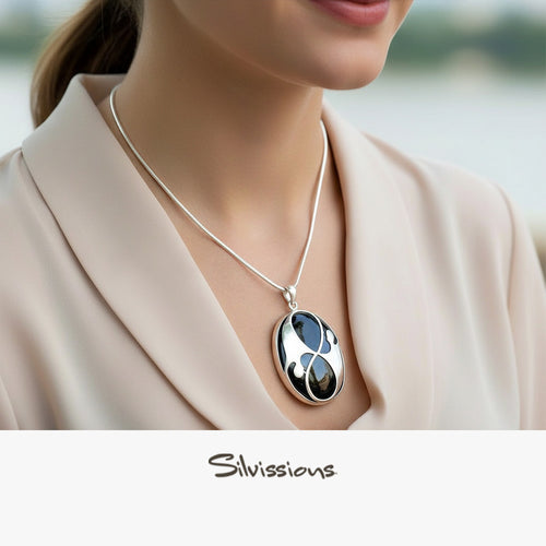 Silver necklace with a pendant worn by a person, blurred background, Silvissions brand visible