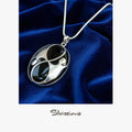 Black onyx pendant on a silver chain against a blue velvet background, with 'Silvissions' branding.