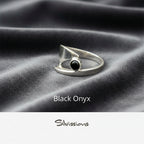 Silver ring with black onyx stone on gray fabric, branded 'Silvissions'.