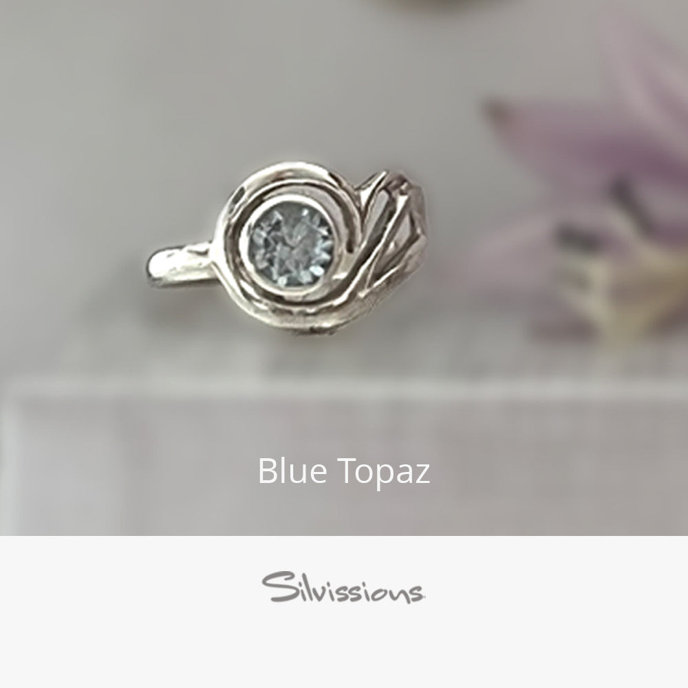 Silver ring with blue topaz gemstone on a neutral background, featuring the brand 'Silvissions'.