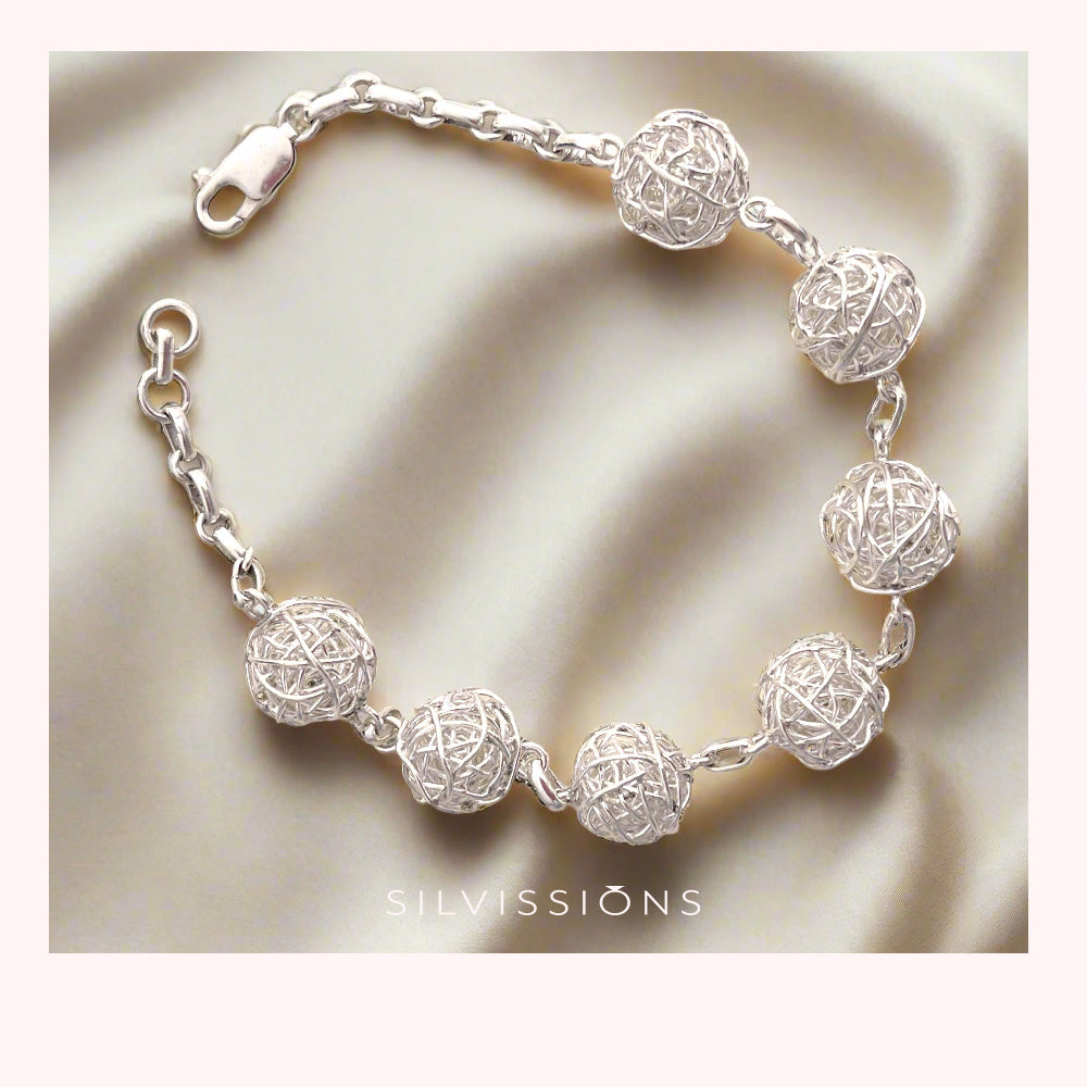 Silver bracelet with spherical designs on a blue satin background, featuring the brand 'Silvissions'.