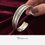 Silver bracelet held by a hand with purple nail polish, brand 'Silvissions' visible