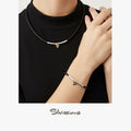 Person wearing a black turtleneck with a triangle pendant necklace and bracelet, brand 'Silvissions' visible.