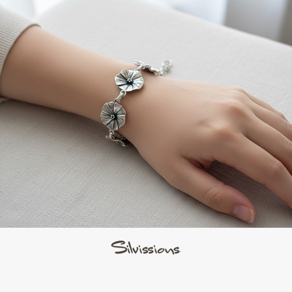 Silver bracelet with floral designs on a wrist against a neutral background, featuring the brand 'Silvissions'.
