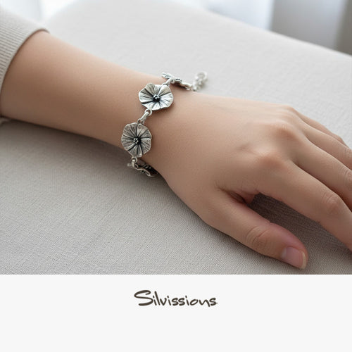 Silver bracelet with floral designs on a wrist against a neutral background, featuring the brand 'Silvissions'.