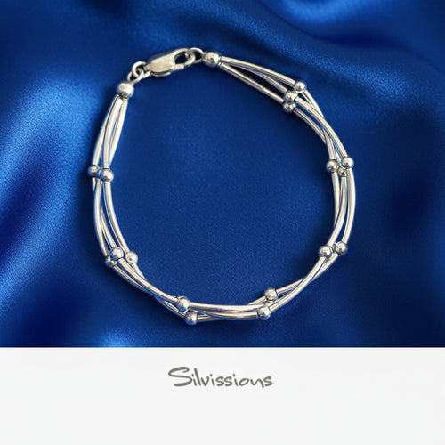 Silver bracelet on blue satin fabric with 'Silvissions' branding.