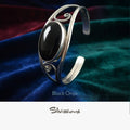 Silver bracelet with black onyx stone on a colorful fabric background, featuring the brand 'Silvissions'.