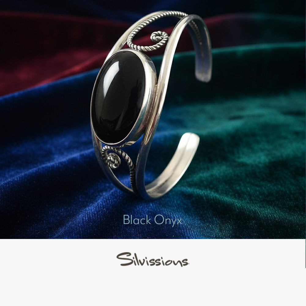 Silver bracelet with black onyx stone on a colorful fabric background, featuring the brand 'Silvissions'.