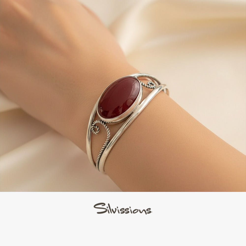 Silver bracelet with a red gemstone on a wrist, brand 'Silvissions' visible