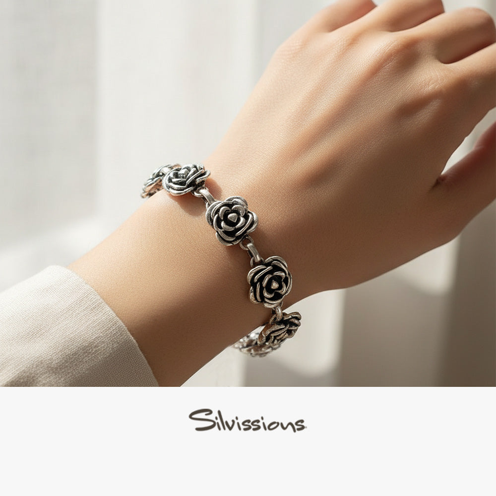 Silver bracelet with floral designs on a wrist, brand 'Silvissions' visible