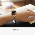 Silver bracelet with a black onyx gemstone on a wrist, blurred background
