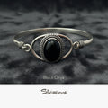 Silver bracelet with a black onyx stone on a dark fabric background, branded 'Silvissions'.