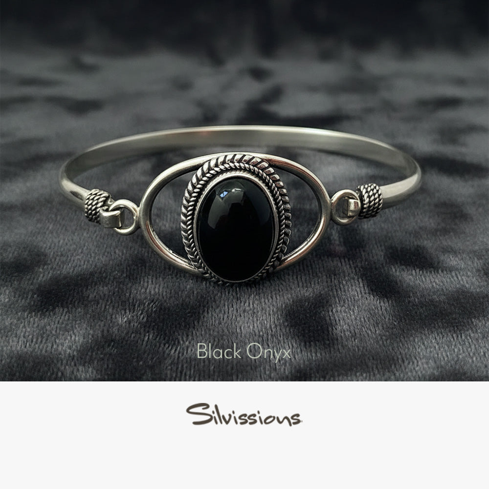 Silver bracelet with a black onyx stone on a dark fabric background, branded 'Silvissions'.